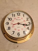 Front view of brass Bulova wall clock showing dial and hands clearly.