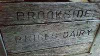 Close up of wooden side panel stamped with 'BROOKSIDE PRICES DAIRY'.
