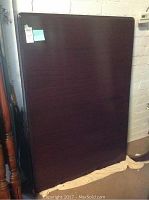 Image of dark finished wooden dining table stored upright.