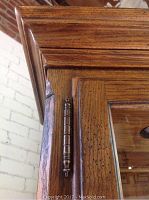 Close-up image showing the detailed metal hinge and corner finish of the wooden china cabinet door.