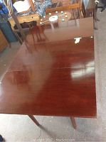 Full view of the wooden table with drop sides in open position showing its rectangular shape and polished top surface.