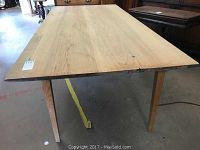 Full view of rectangular wood table showing oak top with visible cracks and paint overspray on edges