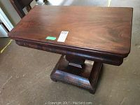 Full view of rectangular antique wooden game table closed with smooth mahogany top and sturdy pedestal base.