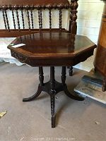 Full view of the vintage octagonal walnut table with turned legs and curved stretcher base.