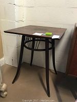 Full view of the square bentwood leg table with round ring base, oak top, and dark finish.