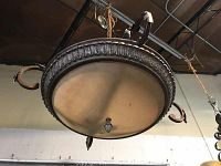 Full view of hanging light fixture suspended from ceiling, showing circular frosted glass shade and metal frame with leaf motif.