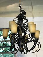 Full view of the black metal hanging light fixture showing nine branches with yellow-tinted glass shades arranged symmetrically.