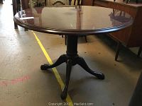 Full view of round table showing walnut look laminate top and pedestal base.