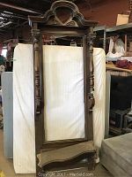 Full front view of wooden mirror frame and shelf standing against backdrop