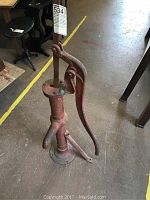 Full view of the old cast iron hand water pump with handle, showing overall condition and size.