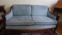Front view of vintage love seat sofa showing light blue upholstery and wooden frame.