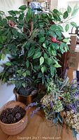Faux indoor tree approximately 40 inches tall beside several faux floral arrangements and a woven basket of pinecones.
