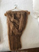 Brown fur stole displayed on a bed, showing the texture and overall condition.