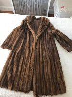 Full view of the vintage mink fur coat laid flat, showing the overall shape, design, and color.