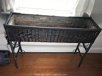 Full view of rectangular wicker planter with metal base insert and metal legs showing overall condition and structure.