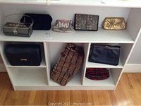 Nine vintage purses and clutches arranged on white shelving unit, showing variety of styles, colors, and materials.