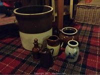 Set of six stoneware pottery items arranged on a carpet showing a large garden planter, various sized jugs, and a vase.
