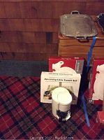 Photo showing boxes including the revolving Lazy Susan set box, a white coffee maker in front, and metal trays stacked on top of a wooden surface.