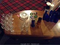 Overview of various glassware and blue glass bottles arranged on a wooden table.