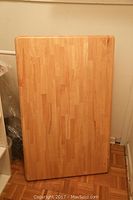 Top-down view of rectangular light wood table showing wood grain and general condition.