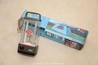 Coleman fluorescent lantern with 3-way switch and boxed Great Basin Tacoma dome tent side by side