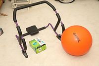 Photo showing the ab roller, new in box, alongside the Gymnastik exercise ball on a floor.