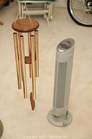Photo showing Iconic Breeze Quadra air purifier and large metal tube wind chime side by side on a floor.