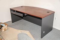 Photo of the large office desk showing the wood veneer top, black base, and open drawer.