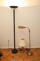 Photo showing all three lamps including the tall black torchiere lamp, the mid-height polished brass adjustable floor lamp, and the small polished brass table lamp with shade.