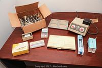 Photo showing the full dental equipment lot including Caulk Vari-mix II-M mixing machine, metal impression trays, dental caulk, and other small dental supply boxes on a table.