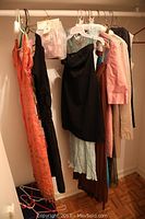 View of multiple women's petite dresses hanging on a closet rod in various colors and styles including a black dress and patterned dresses.