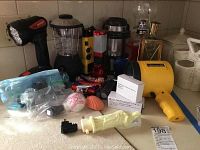 Wide view of the assortment showing various flashlights, lanterns, spotlight, oil lamp, and decorative lights.