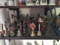 Shelf display showing a wide range of assorted metal bells including plain and decorated ones
