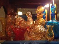 Amber, red, blue, and gold colored glass items including vases, bowls, covered bowls, perfume bottles and decorative pieces.