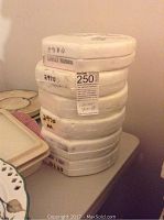 Photo showing a stack of eight boxed collector plates with some visible markings and labels.