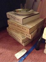 Stack of four Norman Rockwell collector plate boxes with plate on top showing a nature scene with children and balloons.