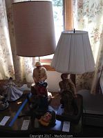 Photo showing two ceramic sailor figure lamps with shades and additional sailor-themed ceramic decor on tabletop near window with floral curtains.