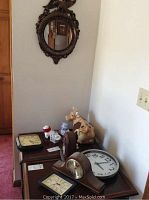 Table-top grouping showing four clocks, cow jar and small figurines beneath oval mirror