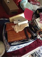 Box with brown crocodile/alligator patterned handbag, some other items including belts visible.