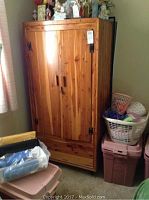 Full front view of cedar wood dresser cabinet in very good condition. Shows two-door design with black metal hinges and wooden handles.