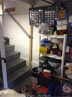 Plastic shelving unit with multiple translucent bins, small parts organizers and a variety of stored tools and cords visible.