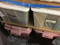 Plastic bins labeled 'Frames' and 'Plaques / Plates' with contents inside, stacked on wooden shelving