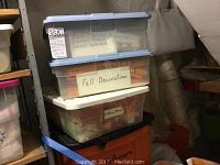 Photo of three stacked plastic storage bins labeled for fall and ribbons-bows containing seasonal decorations