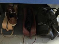 Three pairs of bowling shoes and two bowling ball bags on a shelf