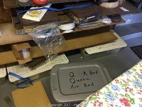 Stack of various supplies and decals stored in plastic containers and cardboard, viewed from a distance.