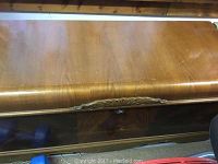 Top view of wooden chest showing polished exterior and carved front detail.