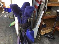 MacGregor golf bag standing upright with multiple golf clubs inside, covered with purple plush headcovers.