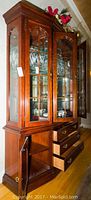 Full front and side view of Thomasville wooden china cabinet with glass doors and shelves and lower drawers and cabinets.