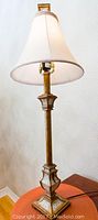 Pair of decorative table lamps shown together, each with bronze/gold bases and white shades.