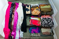 Overview of all scarves unfolded and folded on stairs showing variety of colors and prints.